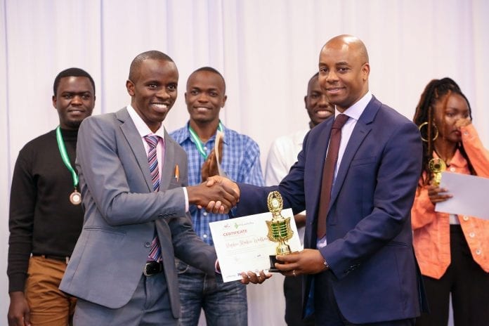 Safaricom Chief Corporate Affairs Officer, Stephen Chege presents a trophy and certificate to Stephen Muchiri Waithanji, a recent JKUAT graduate who emerged the winner during the My Little Big Thing Innovation Challenge