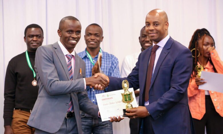 Safaricom Chief Corporate Affairs Officer, Stephen Chege presents a trophy and certificate to Stephen Muchiri Waithanji, a recent JKUAT graduate who emerged the winner during the My Little Big Thing Innovation Challenge