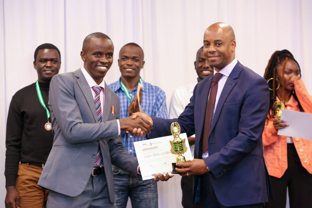 Safaricom Chief Corporate Affairs Officer, Stephen Chege presents a trophy and certificate to Stephen Muchiri Waithanji, a recent JKUAT graduate who emerged the winner during the My Little Big Thing Innovation Challenge