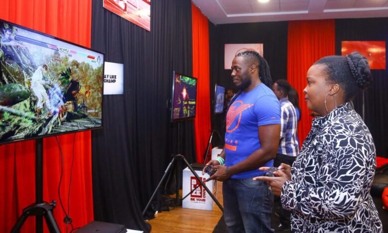 Safaricom Senior Manager Youth Segment Angela Githuthu (Left), Battle it out in a combat play station game with Blaze mentor and professional gamer Brian Diang’a during the Safaricom Blaze e-sports tournament launch.
