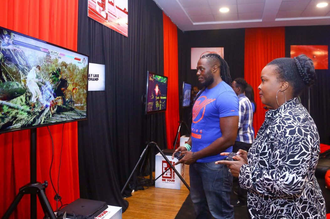 Safaricom Senior Manager Youth Segment Angela Githuthu (Left), Battle it out in a combat play station game with Blaze mentor and professional gamer Brian Diang’a during the Safaricom Blaze e-sports tournament launch.