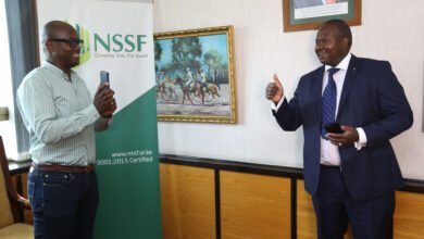CEO NSSF Dr. Antony Omerikwa(right) is shown how to purchase scheme installments service charge through M-PESA by Austin Ouko General Manager NSSF (left), during the announcement of a partnership with Safaricom.