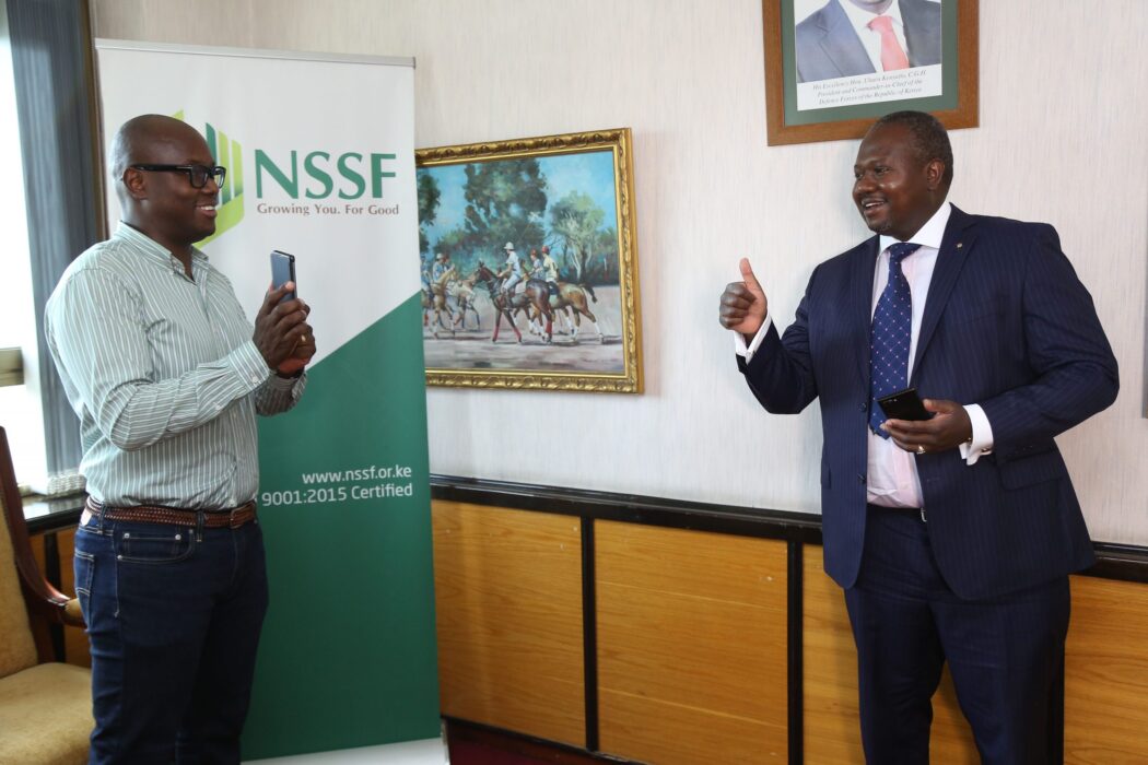 CEO NSSF Dr. Antony Omerikwa(right) is shown how to purchase scheme installments service charge through M-PESA by Austin Ouko General Manager NSSF (left), during the announcement of a partnership with Safaricom.