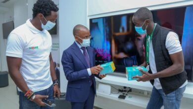 Safaricom Chief Executive Officer Peter Ndegwa, is being taken through the MASOKO products by Dennis Ochieng and Brian Alindi, on how they are used and are now accessible at the shop during the launch of the new Safaricom shop in Moi Avenue.