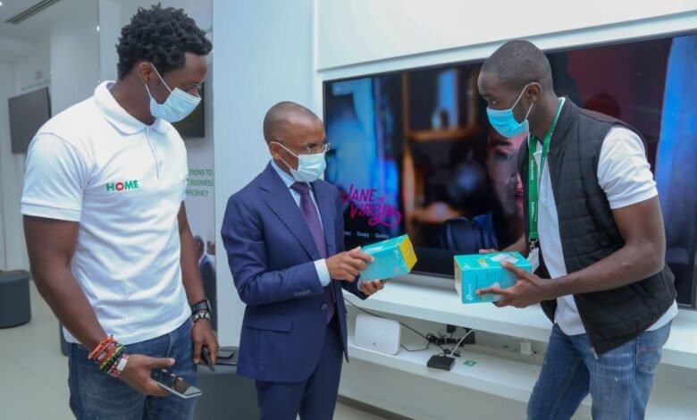 Safaricom Chief Executive Officer Peter Ndegwa, is being taken through the MASOKO products by Dennis Ochieng and Brian Alindi, on how they are used and are now accessible at the shop during the launch of the new Safaricom shop in Moi Avenue.