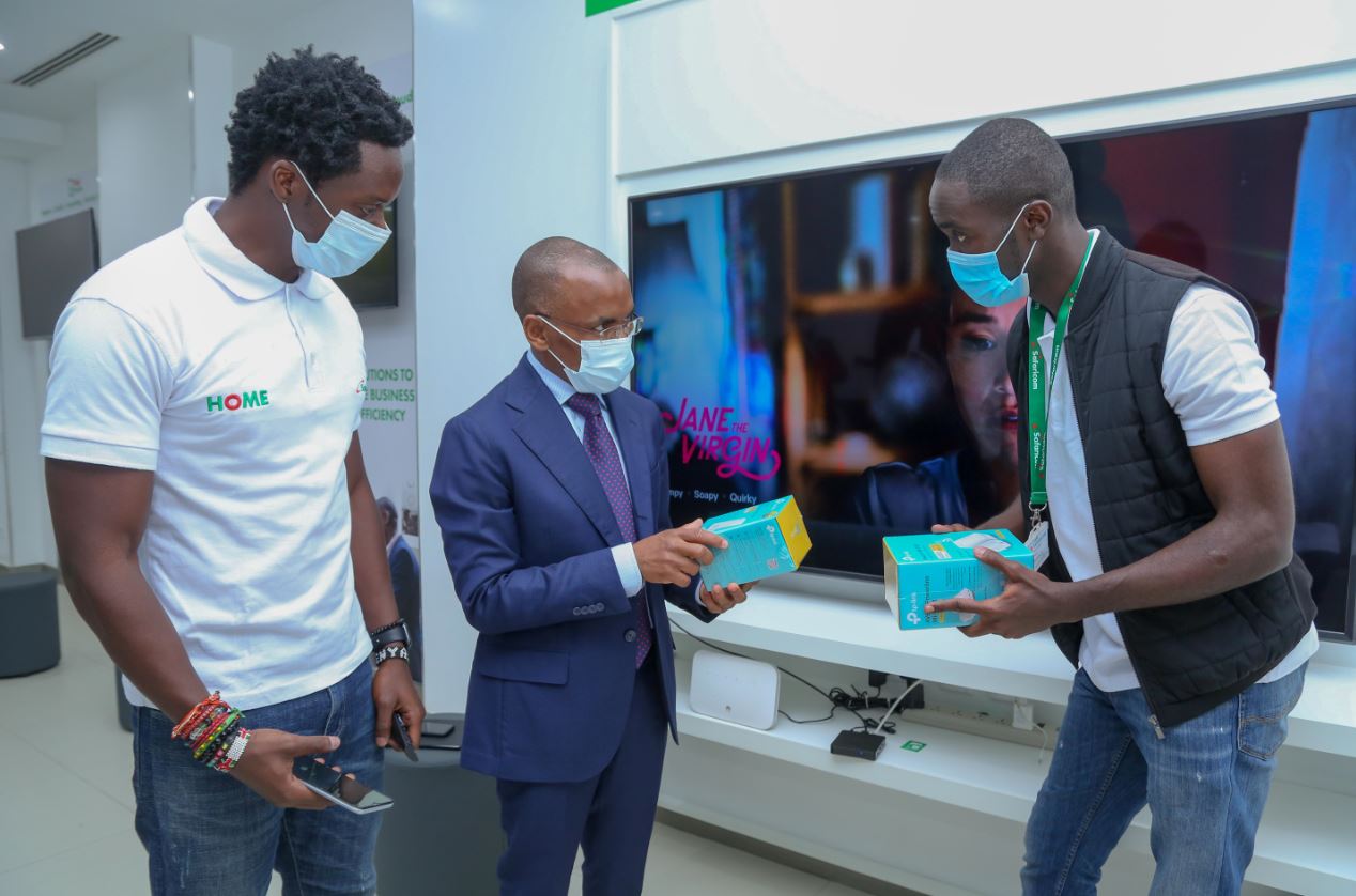Safaricom Chief Executive Officer Peter Ndegwa, is being taken through the MASOKO products by Dennis Ochieng and Brian Alindi, on how they are used and are now accessible at the shop during the launch of the new Safaricom shop in Moi Avenue.