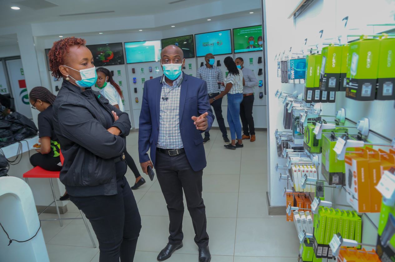 Safaricom Chief Customer Officer Sylvia Mulinge being shown the new phone accessories by Simon Kariithi - Oraimo managing director distributor to Safaricom during the launch of Safaricom newly refurbished Safaricom shop in Moi avenue, Nairobi.