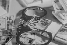 silver handcuffs on top of bundled paper money