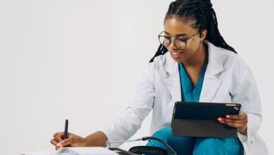 doctor using a tablet and taking notes in a notebook